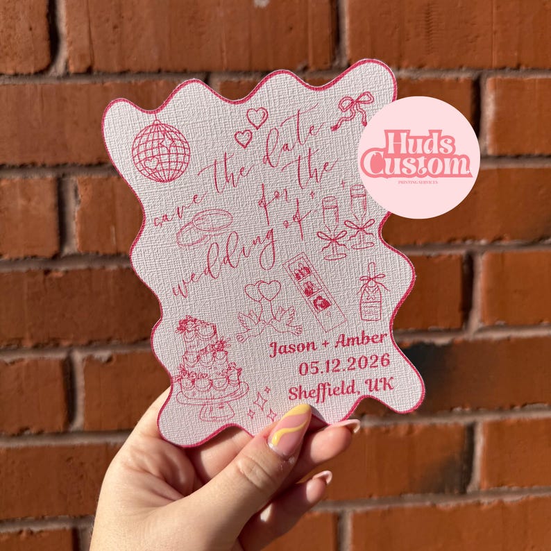 May include: A pink and white wedding invitation with a scalloped edge. The invitation features the text "Save the date for the wedding of" and the names "Jason + Amber" along with the date and location.