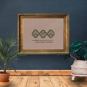 Könnte beinhalten: Ein gerahmtes Kunstwerk mit einem goldfarbenen Rahmen. Das Kunstwerk zeigt drei florale Designs in Grün und Rosa mit Text in einer Fremdsprache darunter. Der Hintergrund des Kunstwerks ist hellbraun.