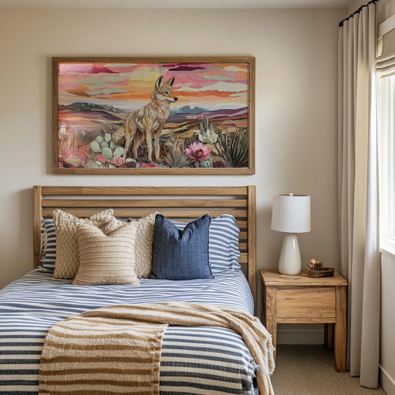 May include: A bedroom scene featuring a wooden bed frame with a striped blue and white comforter. Decorative pillows in beige and blue hues are arranged on the bed. A framed artwork of a coyote in a desert landscape hangs above the bed.