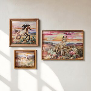 May include: Three framed art pieces with a rustic aesthetic. The artworks depict a horse, a deer, and a coyote in a desert landscape. The frames are made of wood. The color palette includes warm tones of brown, pink, and orange.