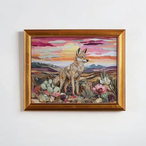 May include: Framed artwork featuring a coyote in a desert landscape. The artwork has a warm color palette with pink, orange, and purple hues in the sky. The coyote is tan and brown, standing among cacti and flowers.