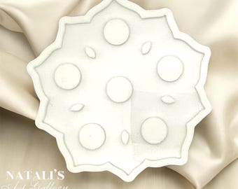 Può includere: Vassoio in ceramica bianca con un design floreale decorativo e sette rientranze circolari. Il vassoio è perfetto per contenere piccoli oggetti, come gioielli o candele.