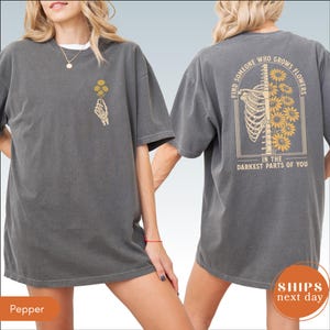 A woman wearing a gray t-shirt with a graphic design on the back.