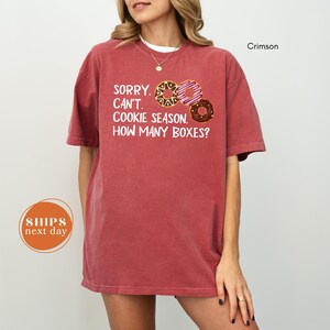 A woman wearing a red t-shirt with a humorous text printed on it, posing against a white background.