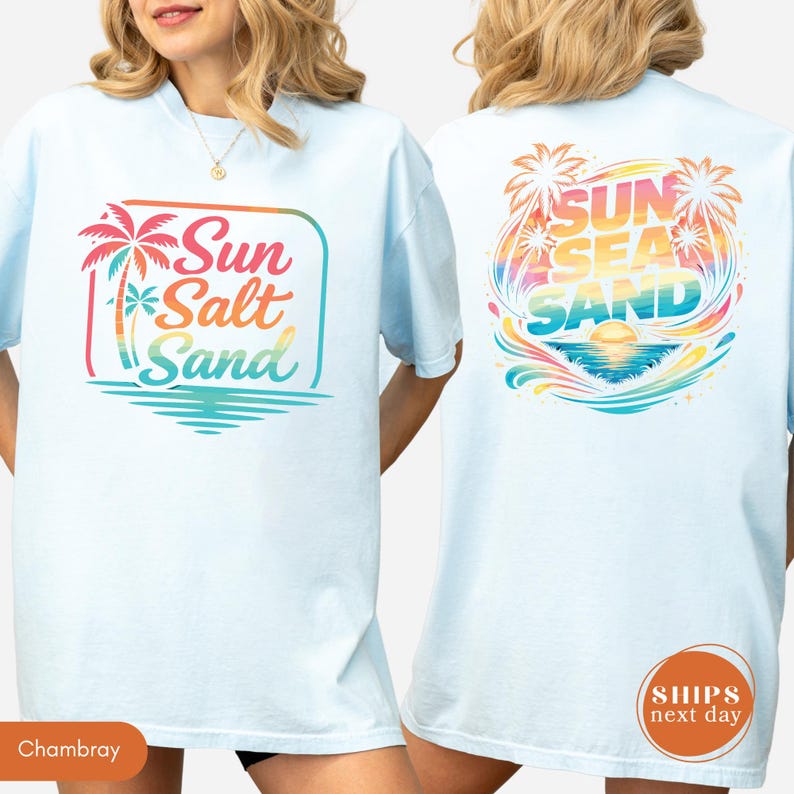 May include: A light blue t-shirt featuring a front graphic with a palm tree and the text Sun Salt Sand in a gradient of red, orange, and teal. The back graphic displays the text Sun Sea Sand with palm trees, a sunset, and ocean waves.