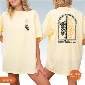 A woman wearing a yellow t-shirt with a graphic design on the back.