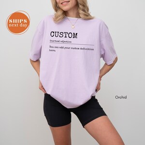 A woman wearing a purple t-shirt with the word "CUSTOM" printed on it, standing against a white background.