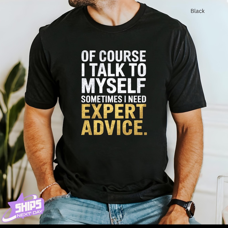 a man wearing a black t - shirt that says of course i talk to my