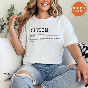 A woman wearing a white t-shirt with the word "CUSTOM" printed on it, sitting on a couch.