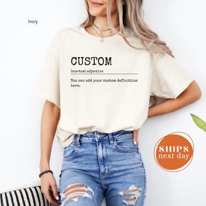 A woman wearing a white t-shirt with the word "CUSTOM" printed on it, standing against a white background.