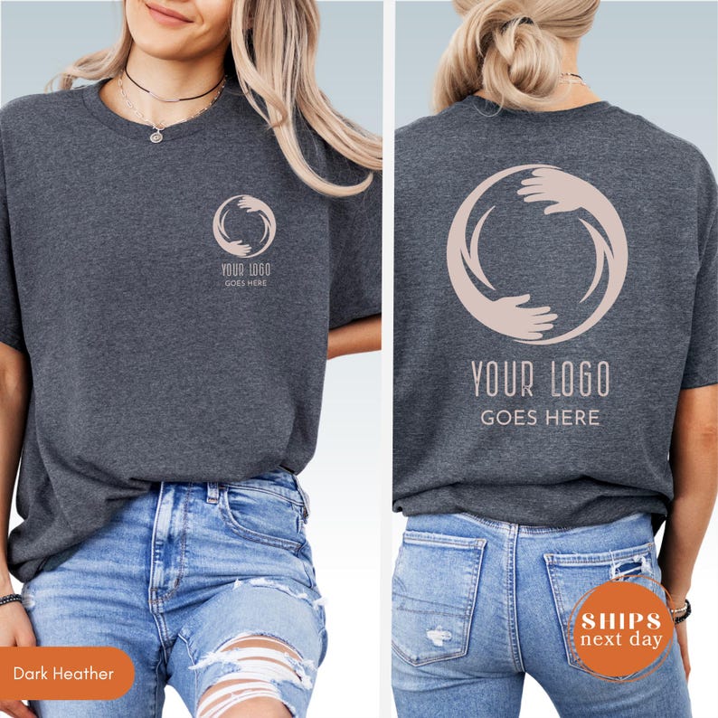 May include: A dark heather gray t-shirt featuring a light pink circular graphic of two hands forming a ring on the left chest and a larger version of the same graphic on the back. The text "YOUR LOGO GOES HERE" is printed below the graphic on both sides.