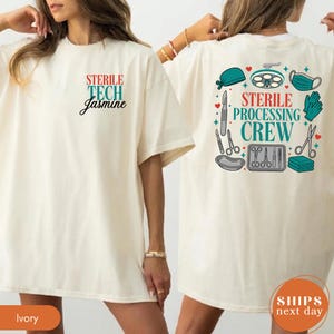 May include: An ivory t-shirt featuring a front chest print that reads Sterile Tech Jasmine. The back displays a large graphic with the text Sterile Processing Crew surrounded by illustrations of surgical tools, a scrub cap, mask, and gloves.