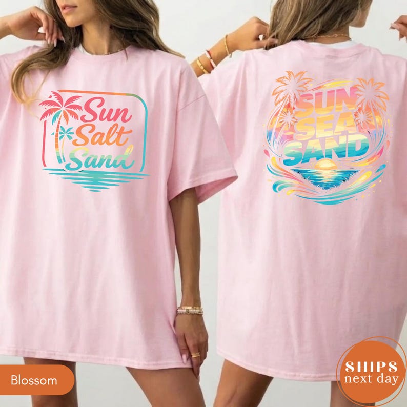 May include: A light pink t-shirt featuring a graphic on the front and back. The front displays a palm tree and the text Sun Salt Sand in a gradient. The back features a larger, circular graphic with palm trees and the text Sun Sea Sand.