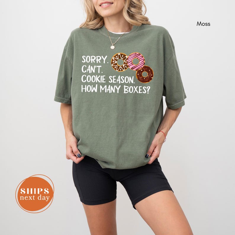 A woman wearing a green t-shirt with a humorous text printed on it, standing against a white background.