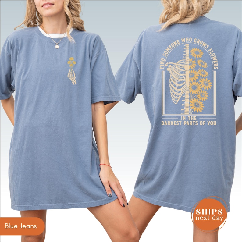 A woman wearing a blue t-shirt with a graphic design on the back.