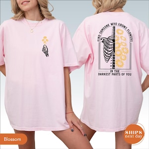 A woman wearing a pink t-shirt with a graphic design on the back.