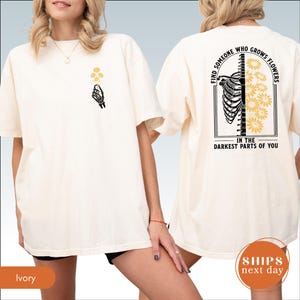 A woman wearing a white t-shirt with a graphic design on the back.