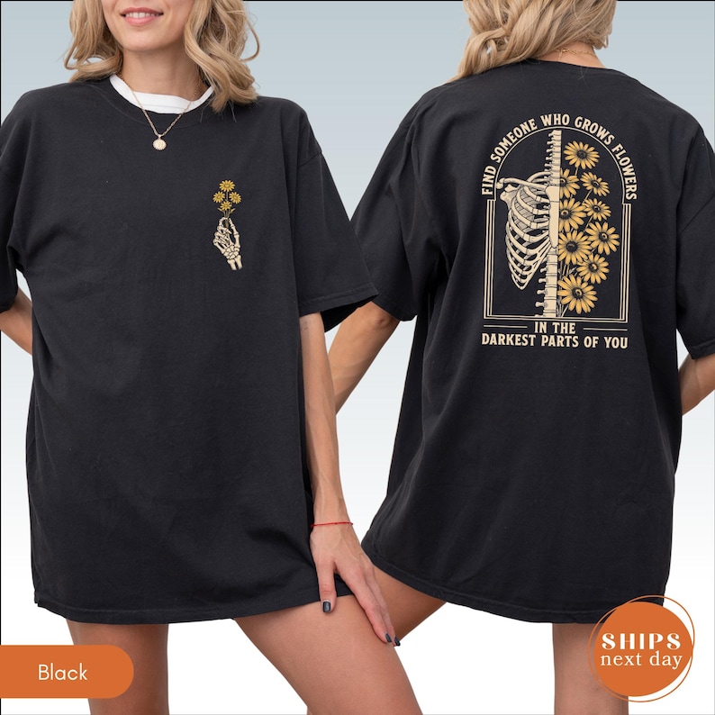 A black t-shirt with a graphic design on the back, featuring a skeleton and flowers.