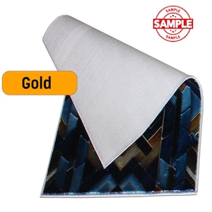 K&ouml;nnte beinhalten: Ein Teppich mit einem geometrischen Muster in Blau- und Braunt&ouml;nen. Der Teppich ist teilweise aufgerollt und zeigt eine wei&szlig;e R&uuml;ckseite. Das Wort "Gold" befindet sich in einem gelben Rechteck. Ein roter "SAMPLE"-Stempel ist sichtbar.