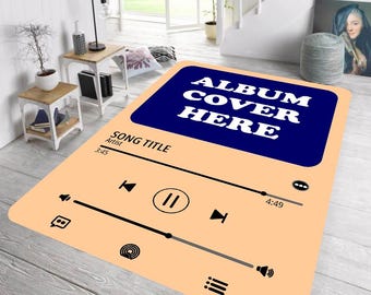 Könnte beinhalten: Rechteckiger Teppich mit pfirsichfarbenem Hintergrund und einem blauen Rechteck in der oberen Mitte mit dem weißen Text "ALBUM COVER HERE". Das Design des Teppichs ahmt eine Musikplayer-Oberfläche nach, mit Play-, Pause- und Skip-Tasten.
