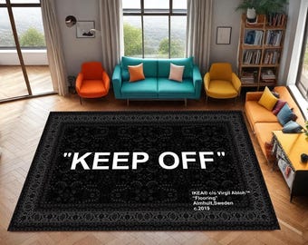 Könnte beinhalten: Schwarzer rechteckiger Teppich mit floralem Muster und den Worten "KEEP OFF" in großen weißen Buchstaben. Der Teppich ist Teil der "Flooring"-Kollektion von IKEA c/o Virgil Abloh, Almhult, Schweden, c.2019. Der Teppich befindet sich in einem Wohnzimmer.