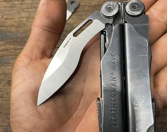 May include: A black Leatherman Wave+ multi-tool with a silver blade and the text "Leatherman Wave+" on the side. The multi-tool is open and the blade is extended.