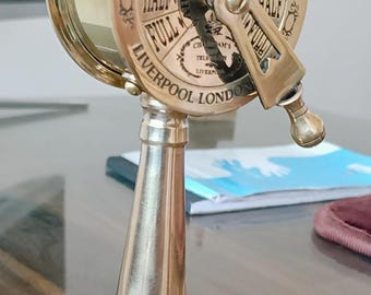 May include: A brass ship's telegraph with a wooden base. The telegraph has a dial with the words "Slow", "Half", "Full", "Stop", and "Stand By". The dial also has the words "Full Speed With Engines" and "Slow Half". The telegraph is labeled "Ship Telegraph" and "Liverpool London".