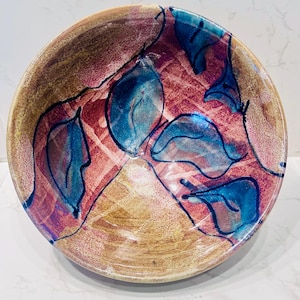 May include: A ceramic bowl with an abstract design in shades of brown, red and blue. The bowl has a glossy finish and is hand-painted.
