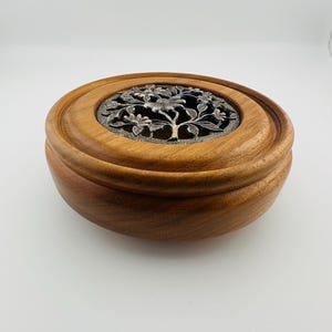 May include: A white ceramic mug with a black handle and the text "But First, Coffee" in a black, handwritten-style font. The mug is on a white surface.