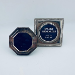 Op de afbeelding: Een achthoekige zilverkleurige fotolijst en een vierkante zilverkleurige fotolijst met een touwachtige rand. De vierkante lijst bevat een zwart inzetstuk met de witte tekst SWEET MEMORIES en de afmetingen 4cm bij 4cm.