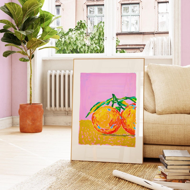 May include: A framed painting depicting two oranges with green leaves against a pink background. The oranges are painted in a vibrant orange, yellow, and red colour scheme.