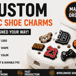 Può includere: Ciondoli per scarpe in PVC personalizzati su uno zoccolo bianco. I ciondoli includono un muso d'orso marrone, una lettera D nera, un pallone da basket arancione, il testo GAME OVER, il numero 23 in rosso e un controller di gioco nero. Testo: CUSTOM PVC SHOE CHARMS.