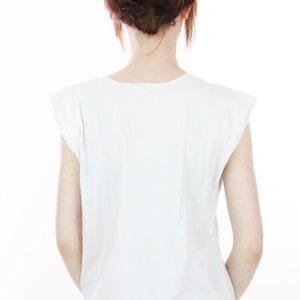 Peut inclure: Un t-shirt blanc sans manches avec un col rond. Le t-shirt est fait d'un tissu doux et confortable et a une coupe d&eacute;contract&eacute;e.