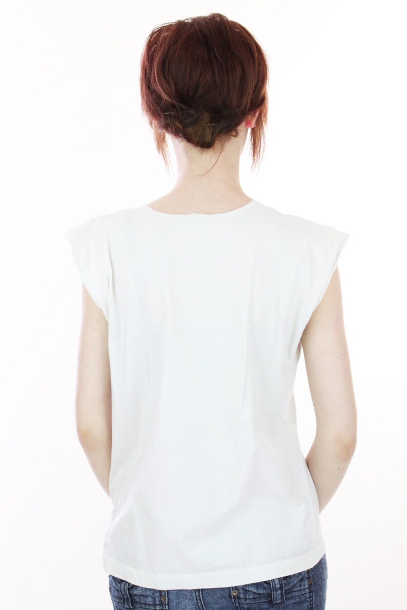 Peut inclure: Un t-shirt blanc sans manches avec un col rond. Le t-shirt est fait d'un tissu doux et confortable et a une coupe d&eacute;contract&eacute;e.