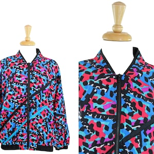 May include: A colorful, abstract patterned jacket with a zipper closure. The jacket is made of a lightweight fabric and has a relaxed fit.