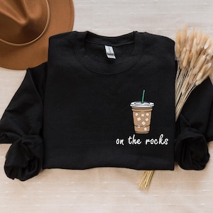 May include: Black sweatshirt with a white graphic of a coffee cup with ice and the text "on the rocks".