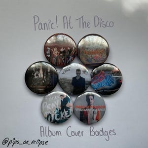May include: A selection of seven circular badges featuring album art from Panic! At The Disco. The badges display various album covers, including band member images and album titles. The text "Album Cover Badges" is written below the badges.