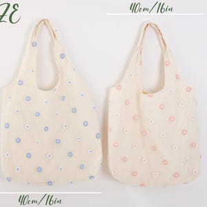 K&ouml;nnte beinhalten: Zwei Einkaufstaschen mit Blumenmustern. Die Tasche links hat ein hellblaues Blumenmuster und die Tasche rechts ein rosa Blumenmuster. Beide Taschen sind 40 cm/16 Zoll breit und 60 cm/24 Zoll hoch.