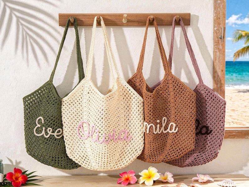 Puede incluir: Cuatro bolsos de ganchillo en verde oliva, crema, marr&oacute;n claro y rosa polvoriento colgados en un perchero de madera. Cada bolso presenta un patr&oacute;n de malla abierta y un nombre personalizado en letra cursiva: Eve, Olivia, Mila y otro.