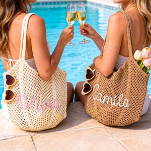 Puede incluir: Dos bolsos de ganchillo, uno color crema y otro tostado, cada uno con un nombre personalizado bordado en cursiva. El bolso crema muestra el nombre Olivia en rosa, mientras que el bolso tostado muestra Camila en blanco. Ambos bolsos tienen gafas de sol en forma de coraz&oacute;n.