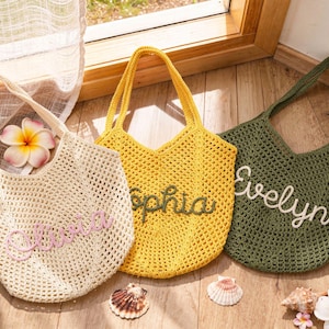 Puede incluir: Tres bolsos de ganchillo en color crema, amarillo y verde oliva. Cada bolso presenta un dise&ntilde;o de malla abierta con dos asas y un nombre personalizado bordado en letra cursiva en la parte delantera: Olivia en rosa, Sophia en verde y Evelyn en blanco.