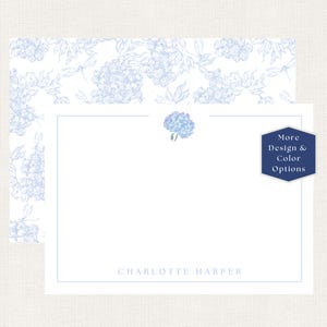 May include: A white stationery card with a light blue hydrangea illustration at the top center and the name Charlotte Harper printed at the bottom. The card features a thin blue border and is paired with a matching envelope with a blue floral pattern.