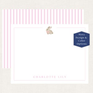May include: A white stationery card featuring a small watercolor illustration of a brown bunny with a pink bow at the top center and the name CHARLOTTE LILY in pink text at the bottom, set against a background with vertical pink stripes.