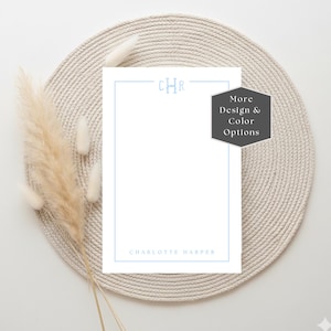 May include: A white rectangular stationery card featuring a light blue border, a centred monogram with the letters CHR, and the name Charlotte Harper printed at the bottom. A dark grey hexagonal badge displays the text More Design & Colour Options.