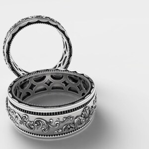 Puede incluir: Dos anillos de plata con dise&ntilde;os intrincados. El anillo superior tiene un dise&ntilde;o simple y redondeado, mientras que el anillo inferior tiene un dise&ntilde;o m&aacute;s elaborado y con patrones.