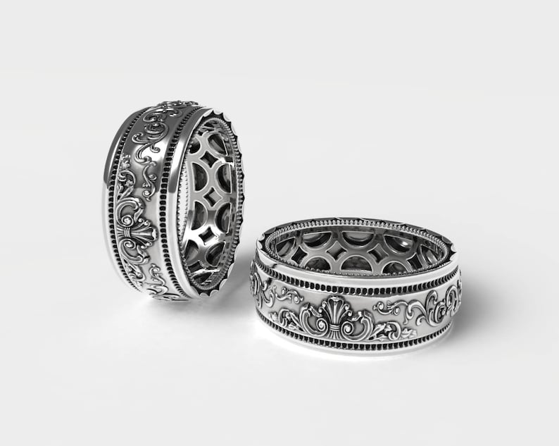 Puede incluir: Dos anillos de plata con dise&ntilde;os intrincados y ornamentados. Los anillos son anchos y tienen un patr&oacute;n detallado de espirales y florituras.
