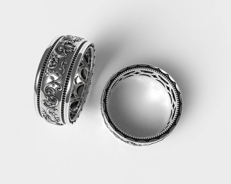 Puede incluir: Dos anillos de plata con dise&ntilde;os intrincados y ornamentados. Los anillos son ambos anchos y tienen un patr&oacute;n detallado en forma de rollo.