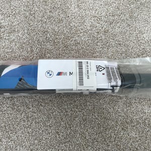 May include: A black and blue umbrella with a white background and the BMW logo. The umbrella is packaged in a clear plastic bag with a white label that says "80 21 2 864 012" and "LDPE".