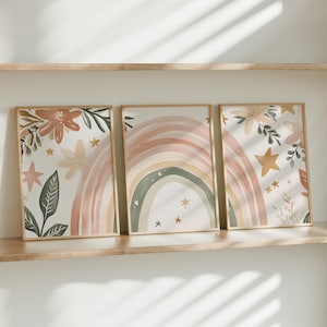 Può includere: Tre stampe artistiche incorniciate ad acquerello con un arcobaleno, fiori e stelle in morbidi colori pastello. L'opera d'arte è esposta su una mensola di legno, creando un'estetica rilassante e stravagante. Le cornici sono di colore marrone chiaro.