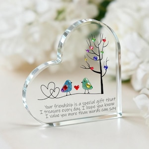 May include: A clear, heart-shaped acrylic keepsake with a tree and two birds. The tree has colorful heart-shaped leaves. The birds are blue and green. Text reads: "Your friendship is a special gift that I treasure every day. I hope you know I value you more than words can say."